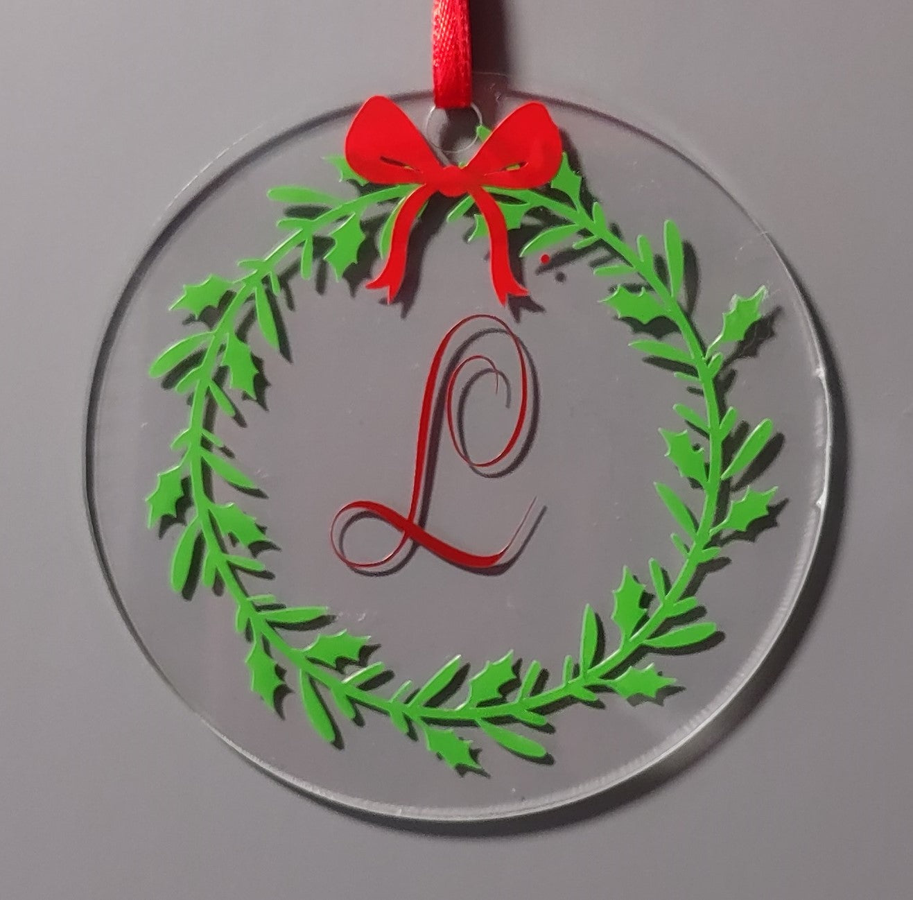 Decorative ornament with green wreath, red bow, and monogram 'L'