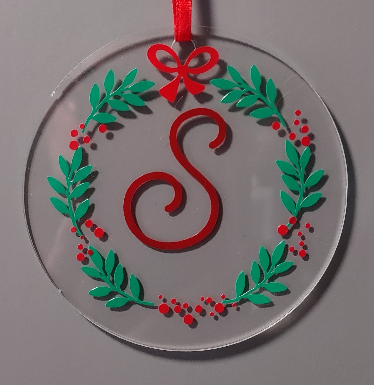 Decorative Christmas ornament with a red 'S' and green leaves